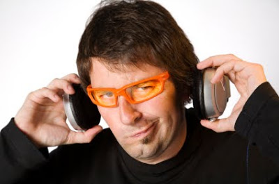 Young man with glasses take off his headphones making faces.